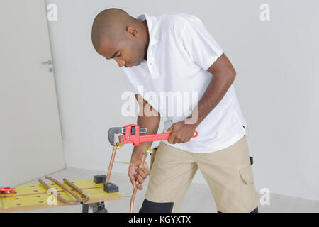 Mann mit einem Schraubenschlüssel auf Kupfer Rohr Stockfoto