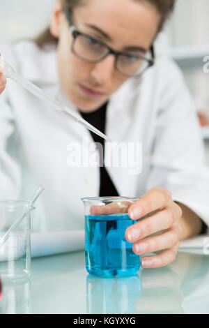 Weibliche Auszubildende arbeiten mit chemischen Flüssigkeiten im Labor Stockfoto