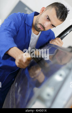 Mechaniker zur Festsetzung einer Autotür mit einem Hammer Stockfoto