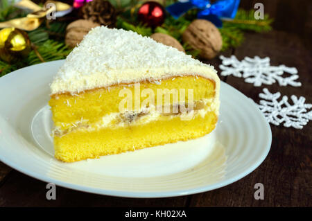 Sanfte Biskuitteig mit cremiger Banane Schicht, Kokosnuss bestreuen. Option festlichen Nachtisch für Weihnachten, Silvester. close-up Stockfoto