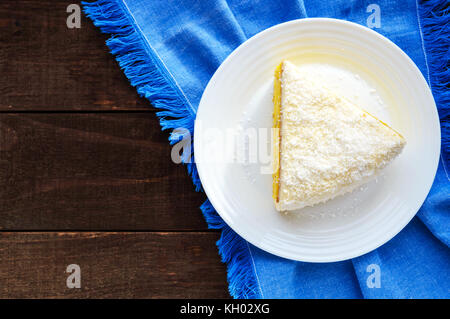 Sanfte Biskuitteig mit cremiger Banane Schicht, Kokosnuss bestreuen. Option festliches Dessert. close-up. die Ansicht von oben. Stockfoto