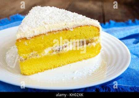 Sanfte Biskuitteig mit cremiger Banane Schicht, Kokosnuss bestreuen. Option festliches Dessert. close-up. Stockfoto