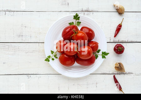 Saftig Scharf marinierte Tomaten auf einem weißen Teller. auf hellem Hintergrund, Ansicht von oben. Stockfoto