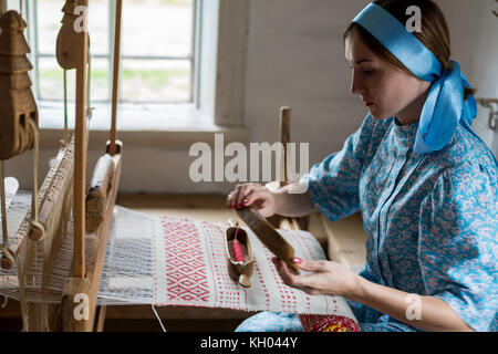 Die Frau ist das Weben der bunte Baumwolle Bademantel oder Kleid durch die Verwendung von Holz- Webstuhl im Dorf in Russland Stockfoto