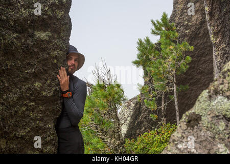 Männliche Kletterer. Kletterer auf einem schwarzen felsige Wand auf dem Ozean Bank in Island klettert, kirkjufjara Strand. Man macht kaum bewegen, ohne Seil. Stockfoto