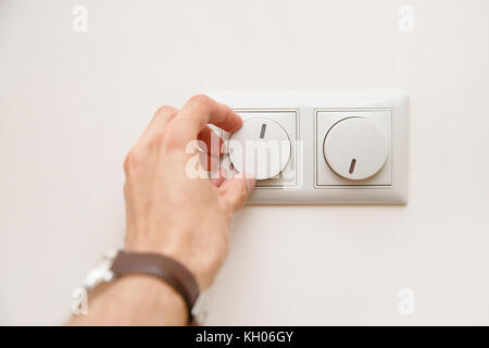 Die Einsparung von Energie Konzept: die menschliche Hand unten Drehende elektrische Licht Dimmer oder Conditioner wärme Controller Stockfoto