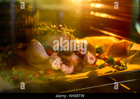 Appetitlich Brathähnchen Türkei mit Orangenscheiben Preiselbeeren und Kräutern im Ofen. Stockfoto