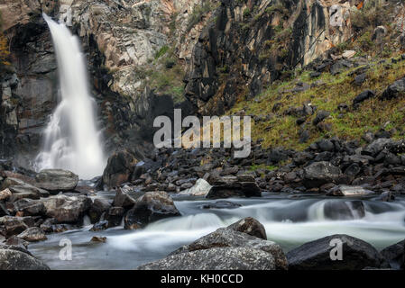 Schönen Blick auf den Wasserfall mit glatten Wasser unter der Felsen und die schwarzen Steine in den Bergen, lange Belichtung Stockfoto