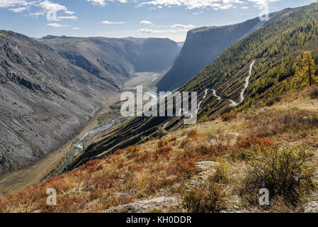 Die malerische Ansicht von oben auf den steilen gewundene Schotterpiste durch den Pass, auf dem Berghang, das Tal zwischen den Bergen und dem Rive Stockfoto