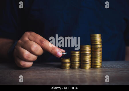 Die Hand des Menschen legen Geld Münzen Münzen zu stapeln. Geld, finanziellen, geschäftlichen Wachstum Konzept Stockfoto