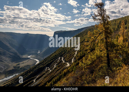 Die malerische Ansicht von oben auf den steilen gewundene Schotterpiste durch den Pass, auf dem Berghang, das Tal zwischen den Bergen und dem Rive Stockfoto