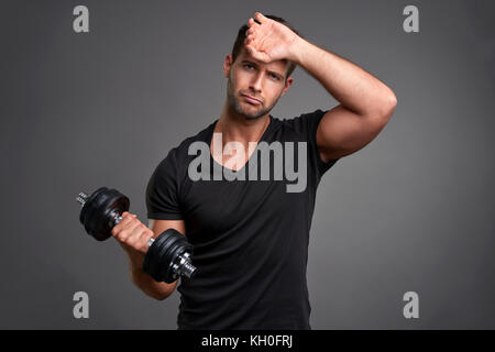 Ein hübscher junger Mann Gewicht heben und müde Stockfoto