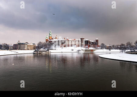 Historischen Königlichen Schloss und Kathedrale auf dem Wawel in Krakau, Polen, mit dem Fluss Weichsel an einem bewölkten Tag im Winter mit Türme der Kathedrale im letzten Sonnenlicht Strahlen Stockfoto