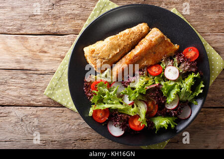 In einem Ramponierten Seehecht und frischen Salat auf einem Schild in der Nähe Fried. horizontal oben Ansicht von oben Stockfoto