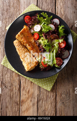 In einem Ramponierten Seehecht und frischen Salat auf einem Schild in der Nähe Fried. Senkrechte Draufsicht von oben Stockfoto