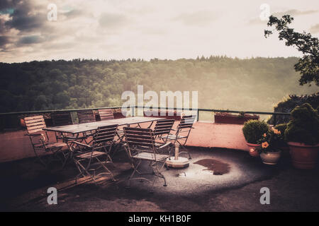 Terrasse mit Holzmöbeln und einem schönen Blick auf den Wald in Morgensonne. vintage, retro-Konzept. Stockfoto