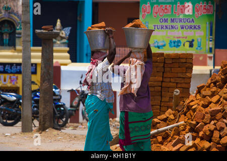 Zwei indische Frauen tragen schwere Steine auf ihre Köpfe in der traditionellen Kleidung. Blick von der Rückseite. Verwendung von weiblichen Arbeitskräften in das Gebäude. Stockfoto