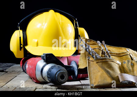 Sicherheit Zubehör und Auswirkungen Hammer Zubehör für ein Builder auf einem Holztisch. schwarzen Hintergrund. Stockfoto