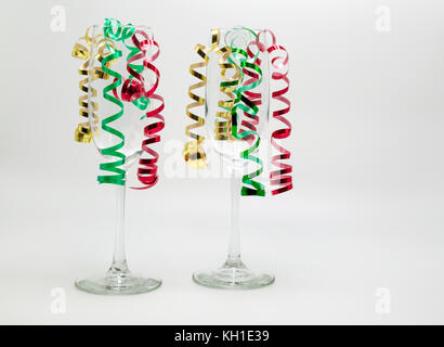 2 Champagnergläser mit Weihnachten curling Ribbon unten von innen Streaming über einen soliden Hintergrund isoliert Stockfoto