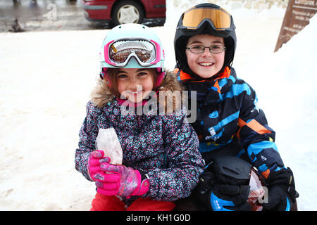 Kinder im Schnee tragen Skianzuege, Helme und Schutzbrillen Stockfoto