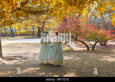 Asiatische Mädchen mit Hanbok (traditionelle koreanische Kleid) und Gelb Herbst Ahorn Blätter in Gyeongbokgung Palast in Seoul, Südkorea. Stockfoto