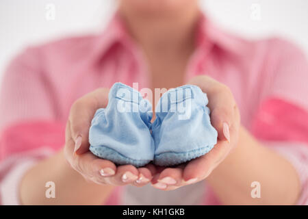 Kleine Schuhe für das ungeborene Kind in den Bauch der schwangeren Frau Stockfoto