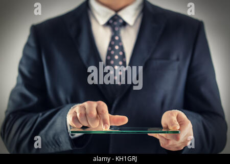 Wirtschaft und Technologie Konzept. Mann in Anzug Holding und zeigen transparent mobile Geräte im Büro, Nahaufnahme Stockfoto