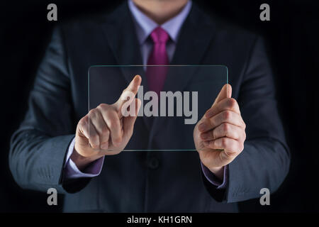 Wirtschaft und Technologie Konzept. Mann in Anzug Holding und zeigen transparent mobile Geräte im Büro, Nahaufnahme Stockfoto