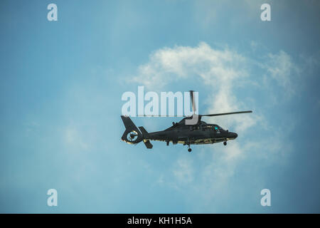 Hubschrauber fliegen gegen den blauen Himmel mit Wolken Stockfoto