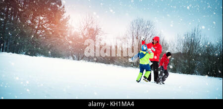 Vater mit Söhnen gehen bei Schneefall Stockfoto