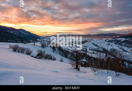 Winter Dawn in bergiger Landschaft. Wunderschöne bewölkter Himmel über die schneebedeckten Hügeln. breite Bergrücken in der Ferne Stockfoto