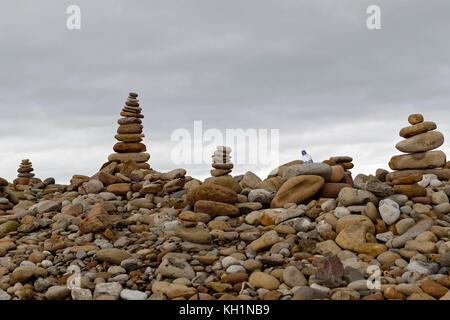 Mann aus Stapeln von Stein/Cairns (& eine Plastikflasche) - Futter das East Beach der heiligen Insel Stockfoto