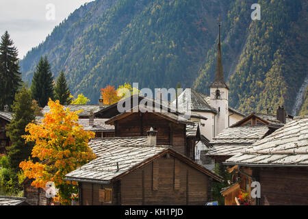 BLATTEN, SCHWEIZ - SEPT. 28, 2017: altes Bergdorf im Herbst mit der kleinen weißen Kirche durch traditionelle Holzhäuser umgeben. Stockfoto