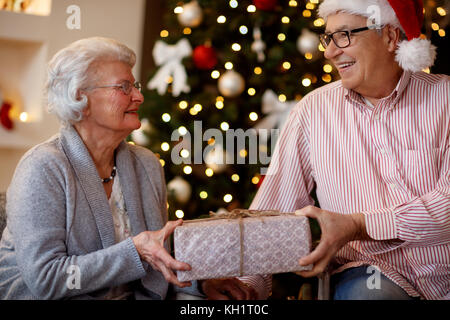 Familie, Urlaub, Alter und Personen Konzept - schönes Lächeln senior Paar mit Weihnachtsgeschenk Stockfoto