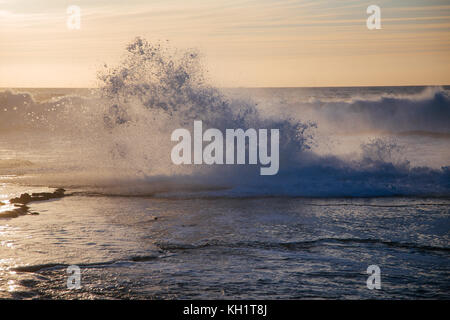 Große Wellen schlagen die Felsen, wie die goldene Sonne an der Küste von Heu el Fath, Rabat, Marokko. Stockfoto
