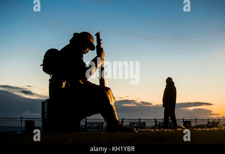 Ein Mann sieht Tommy, eine Statue eines Soldaten aus dem Ersten Weltkrieg, vom Künstler&Ecirc;Ray Lonsdale, an, als die Sonne am Gedenktag in Seaham aufgeht. Stockfoto