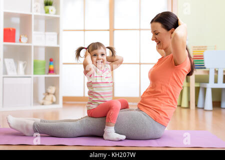 Kind Mädchen und Mutter tun Gymnastik auf der Matte zu Hause Stockfoto