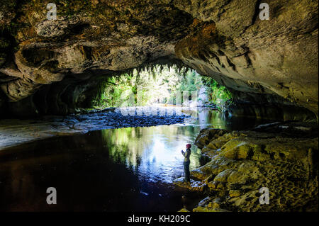 Frau genießen die atemberaubende Moria Gate Arch im Oparara Basin, karamea, Südinsel, Neuseeland Stockfoto