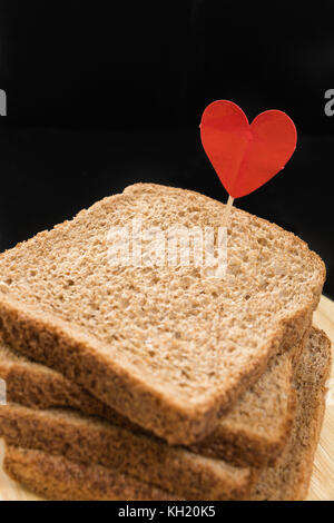 Vollkorn sandwich Brot Scheibe mit Herz Pin, mit dunklem Hintergrund. Stockfoto
