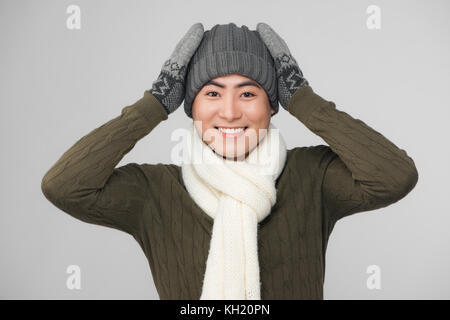 Junge lächelnde asiatischer Mann, gestrickte Pullover und Handschuhe Stockfoto