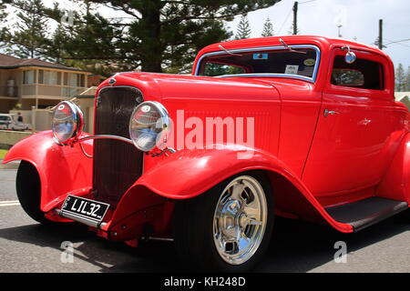 Ein größeres als das Leben hell rot Hot Rod reibungslos Rollen entlang yamba Straßen in der jährlichen Hot Rod show. Zeigen die Besitzer Meisterwerk in der Restaurierung. Stockfoto