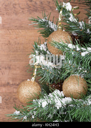 Gold Schmuck hängen an einen Weihnachtsbaum mit einem Holz Hintergrund Stockfoto