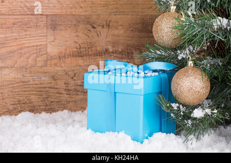 Blaue Geschenkbox durch einen Weihnachtsbaum mit einem Holz Hintergrund Stockfoto