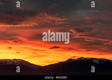 Bunte Landschaft mit Bergen und Schnee gelb und orange Himmel mit Wolken bedeckt, beleuchtete Sun bei Sonnenaufgang Stockfoto