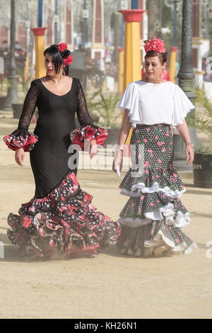 Zwei Damen, die auf dem staubigen Messegelände spazieren, Jerez de la Frontera, Feria de Caballo, May Horse Fair, Cadiz, Andalusien, Spanien. Stockfoto