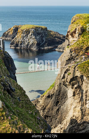 Tausende von Touristen, die Carrick-a-rede rope bridge in County Antrim in Nordirland, hängende 30 m über Felsen und Spanning 20 m, Anbindung des wichtigsten Stockfoto