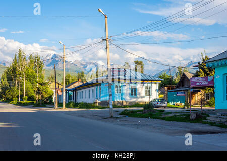 KARAKOL, KIRGISISTAN - 2. AUGUST: Blick über die Straße mit Autos und Geschäften in Karakol Stadt. August 2016 Stockfoto