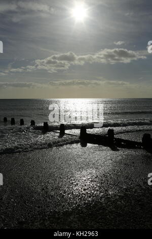 Bognor Regis. Die Sonne reflektiert vom Meer an einem verlassenen South Coast Beach in Großbritannien. Ruhiges Meer, Ebbe. Zeigt holzhaltige Wellenbrecher, um Küstenerosion zu verhindern. Stockfoto