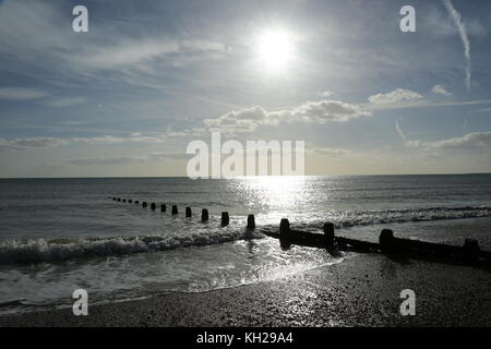 Bognor Regis. Die Sonne reflektiert vom Meer an einem verlassenen South Coast Beach in Großbritannien. Ruhiges Meer, Ebbe. Zeigt holzhaltige Wellenbrecher, um Küstenerosion zu verhindern. Stockfoto