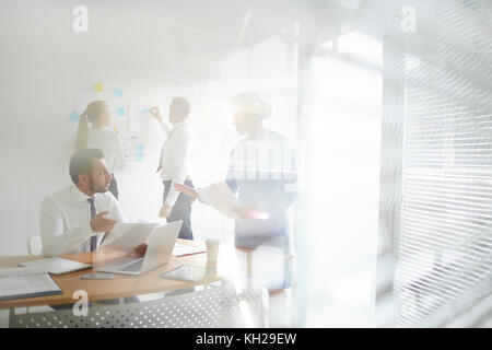 Junge und reife Finanziers diskutieren über Finanzpapiere im Arbeitsumfeld Stockfoto